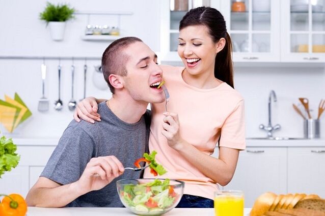 djevojka hrani muškarca vitaminskom salatom za potenciju